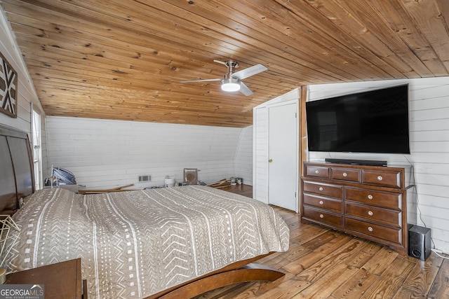 bedroom with wood walls, vaulted ceiling, light hardwood / wood-style flooring, wooden ceiling, and ceiling fan