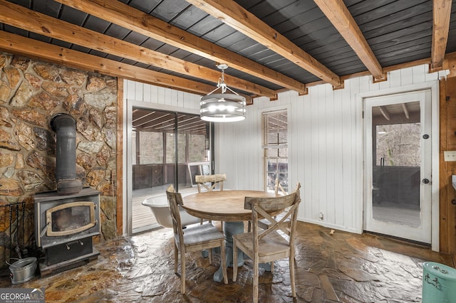 unfurnished dining area featuring a wood stove and beam ceiling