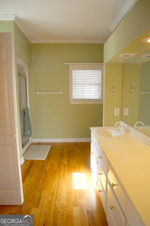 bathroom with vanity, ornamental molding, hardwood / wood-style floors, and walk in shower