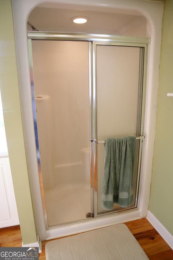 bathroom with an enclosed shower and hardwood / wood-style floors