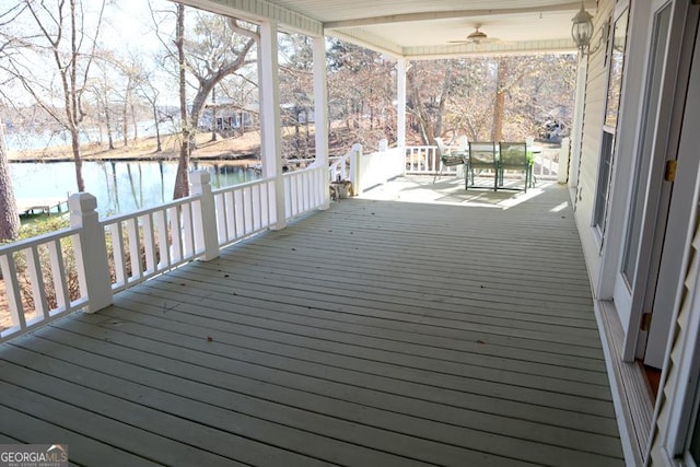 wooden deck with ceiling fan and a water view