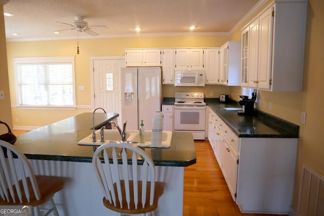 kitchen featuring white cabinetry, ornamental molding, white appliances, and light wood-type flooring