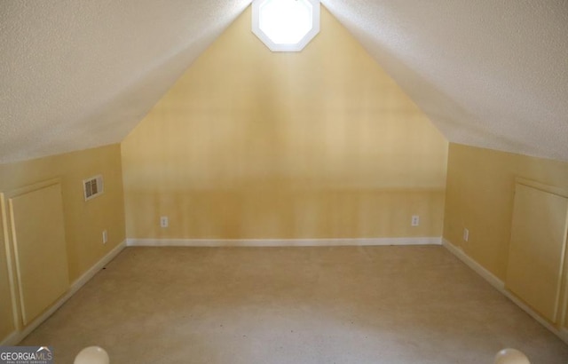 additional living space with vaulted ceiling and a textured ceiling