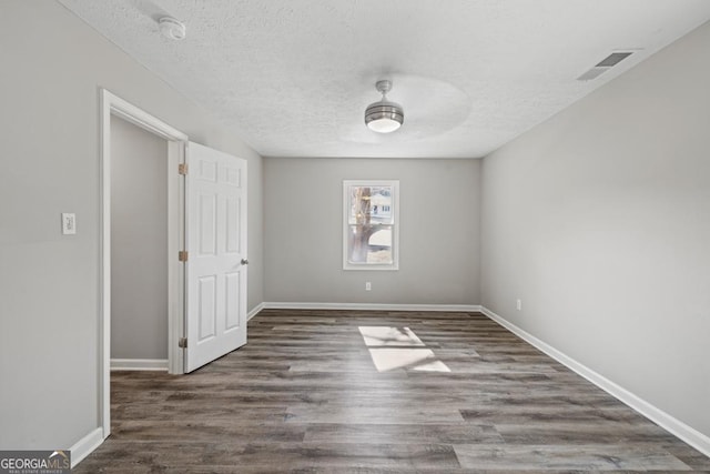 unfurnished room with dark wood-type flooring and a textured ceiling