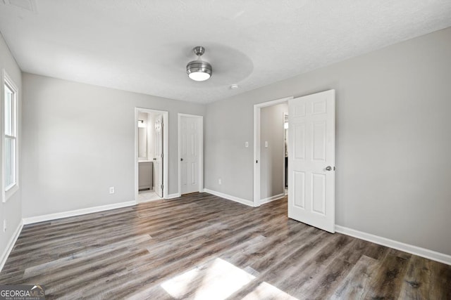 unfurnished bedroom featuring ceiling fan, ensuite bathroom, and dark hardwood / wood-style floors