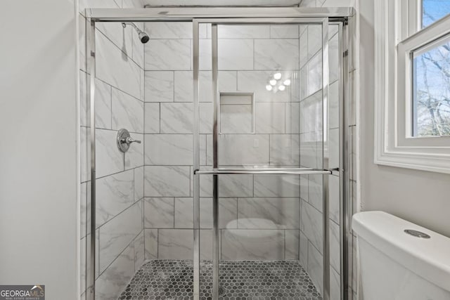 bathroom with a shower with shower door and toilet