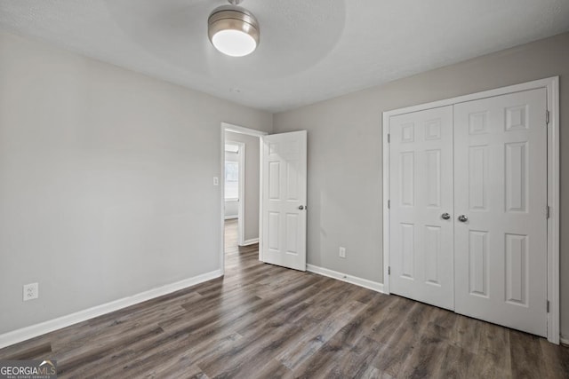 unfurnished bedroom featuring dark wood-type flooring, ceiling fan, and a closet