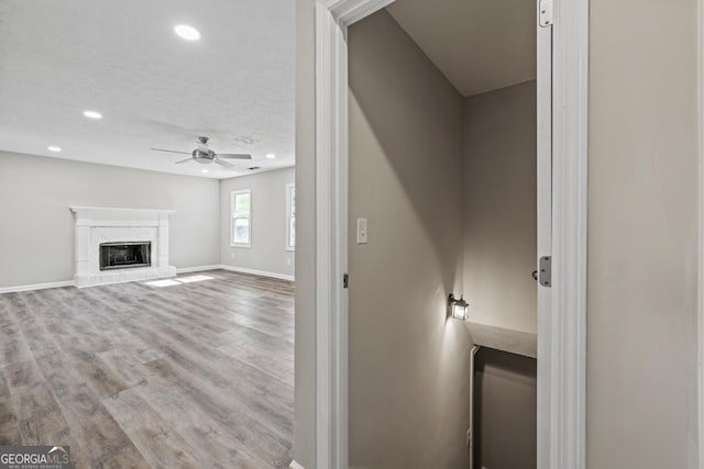 interior space featuring a textured ceiling, a fireplace, ceiling fan, and light wood-type flooring