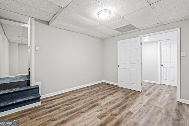 basement with hardwood / wood-style floors and a paneled ceiling