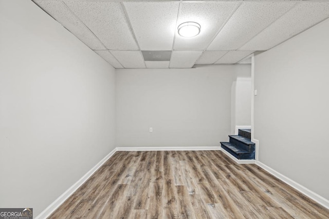 basement featuring a drop ceiling and light hardwood / wood-style floors