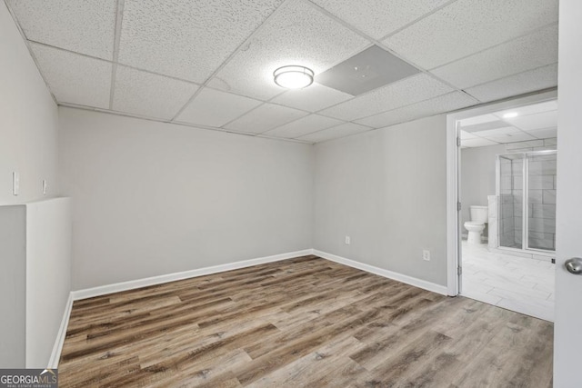 empty room with a drop ceiling and hardwood / wood-style floors