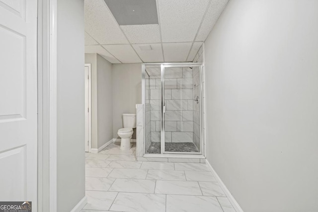 bathroom with a shower with shower door, toilet, and a paneled ceiling