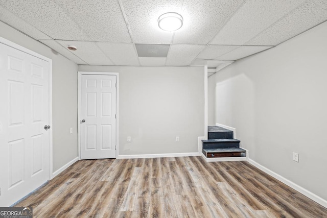 basement featuring a paneled ceiling and light hardwood / wood-style flooring