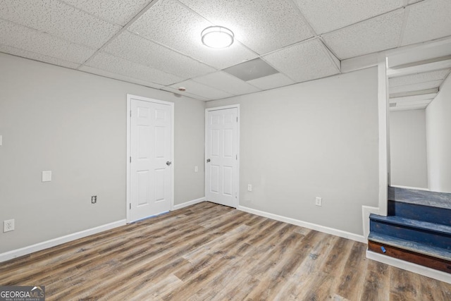 basement with wood-type flooring and a paneled ceiling