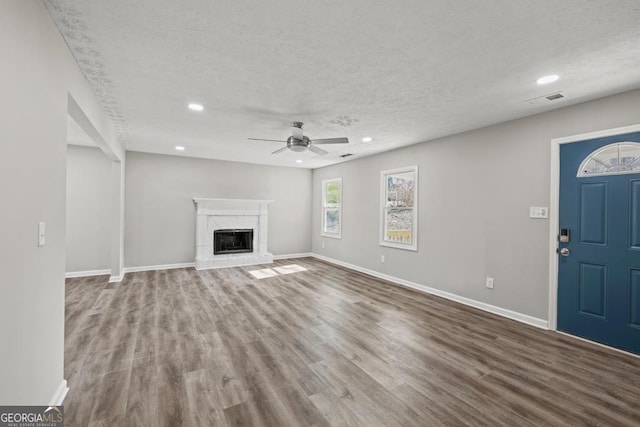 unfurnished living room featuring hardwood / wood-style flooring, ceiling fan, and a textured ceiling