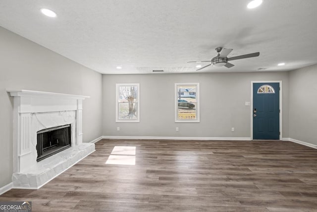 unfurnished living room with wood-type flooring, a textured ceiling, ceiling fan, and a high end fireplace