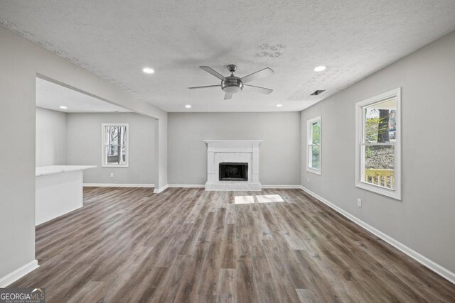 unfurnished living room with dark hardwood / wood-style flooring, ceiling fan, a textured ceiling, and a high end fireplace