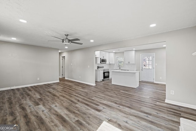 unfurnished living room featuring ceiling fan and dark hardwood / wood-style flooring