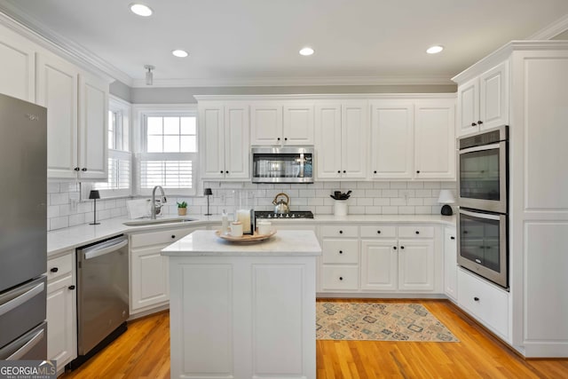 kitchen featuring white cabinetry, sink, a center island, light hardwood / wood-style floors, and stainless steel appliances