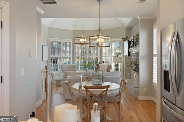 dining room with ornamental molding, plenty of natural light, a chandelier, and light wood-type flooring