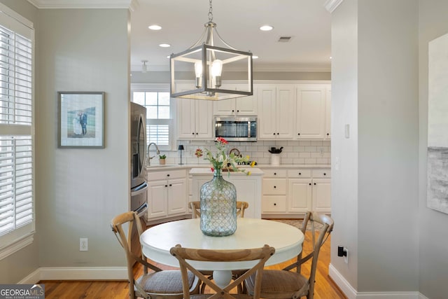 dining room featuring ornamental molding, sink, an inviting chandelier, and light hardwood / wood-style floors