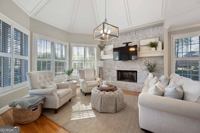 living room with crown molding, a brick fireplace, hardwood / wood-style floors, and a chandelier