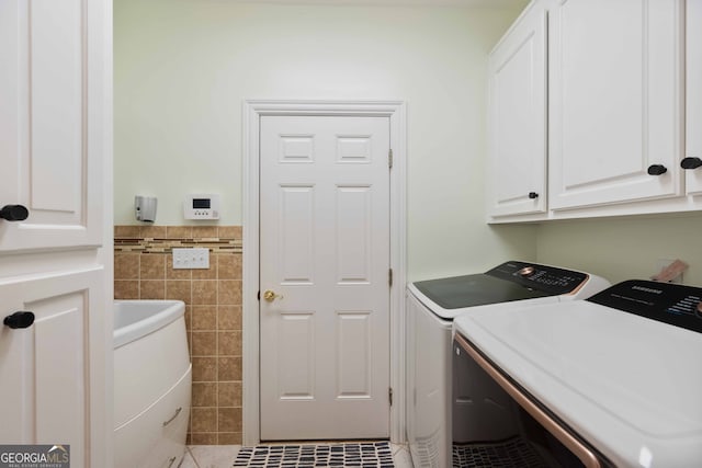 washroom featuring tile walls, washer and clothes dryer, tile patterned floors, and cabinets