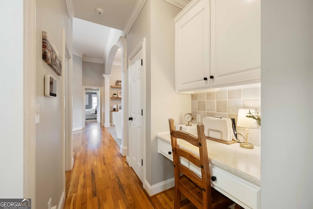 hall featuring decorative columns, crown molding, and hardwood / wood-style floors