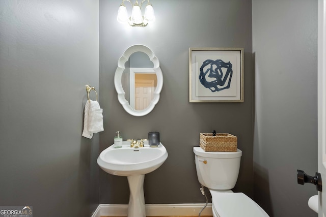 bathroom featuring toilet and a notable chandelier