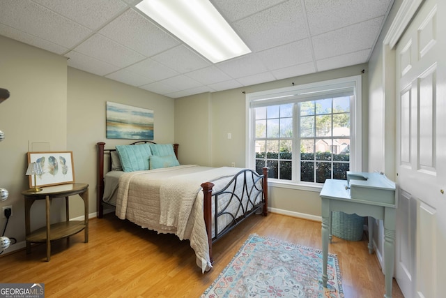 bedroom with a paneled ceiling and light hardwood / wood-style flooring