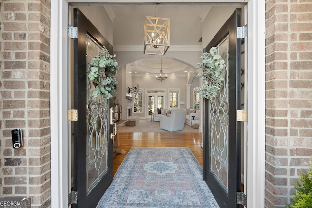 entrance foyer featuring an inviting chandelier, hardwood / wood-style flooring, crown molding, and a raised ceiling