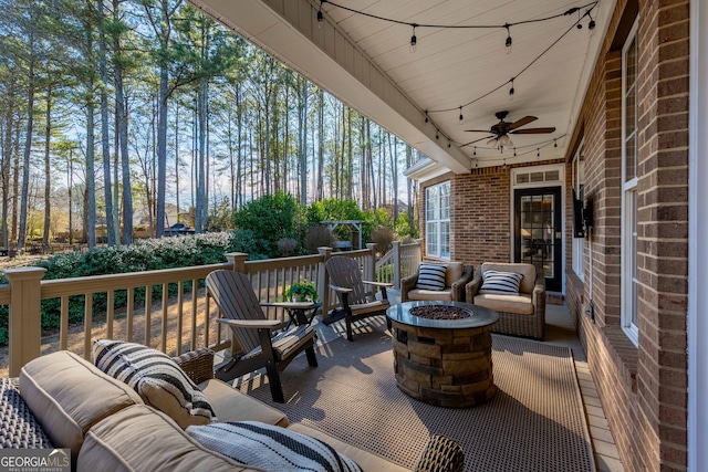 view of patio with ceiling fan and an outdoor living space with a fire pit