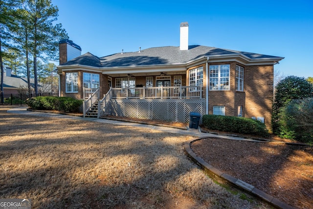 back of property with ceiling fan, covered porch, and a lawn