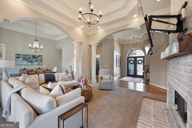 living room with crown molding, a raised ceiling, and a chandelier