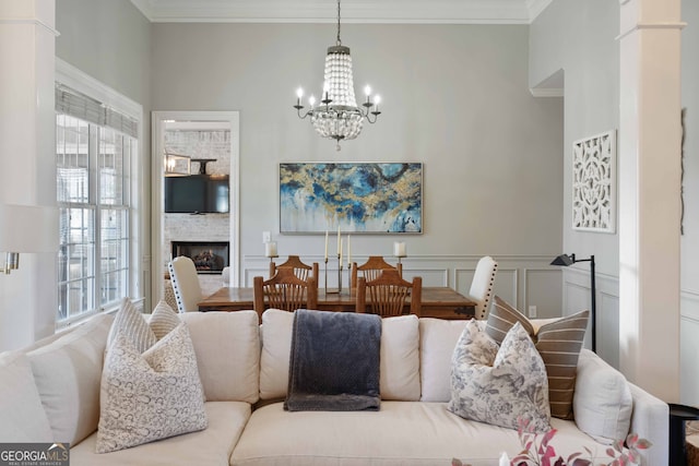 living room featuring crown molding, an inviting chandelier, and a fireplace