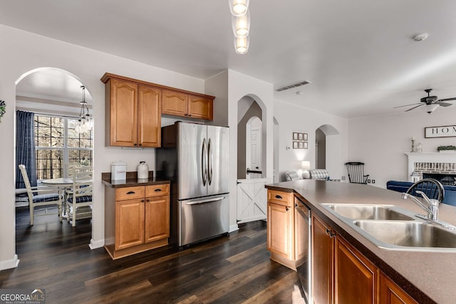 kitchen featuring appliances with stainless steel finishes, a fireplace, dark hardwood / wood-style flooring, and sink