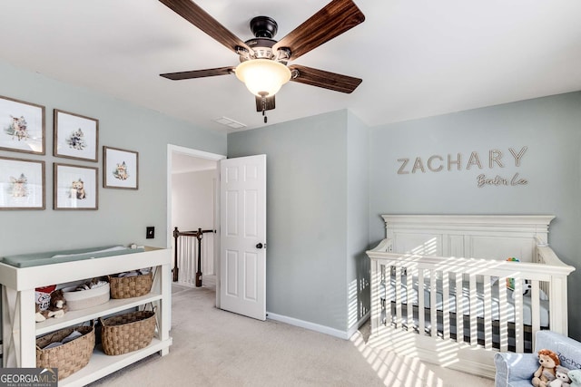 carpeted bedroom with ceiling fan and a crib