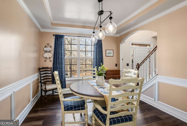 dining space with dark hardwood / wood-style flooring, a tray ceiling, and crown molding