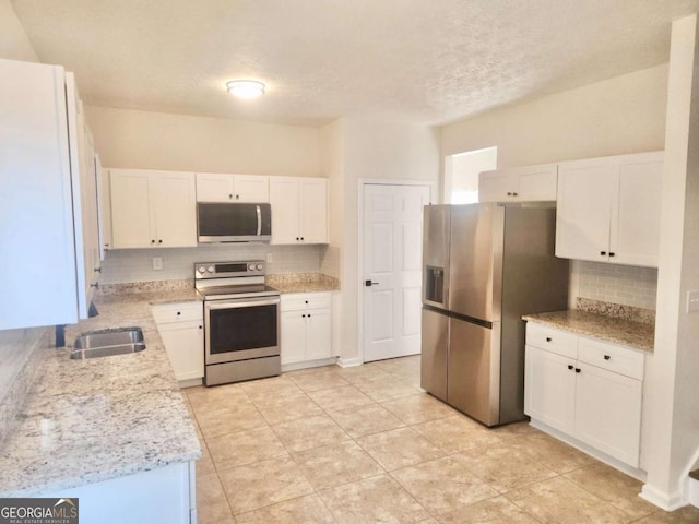 kitchen featuring light stone countertops, white cabinetry, appliances with stainless steel finishes, and sink