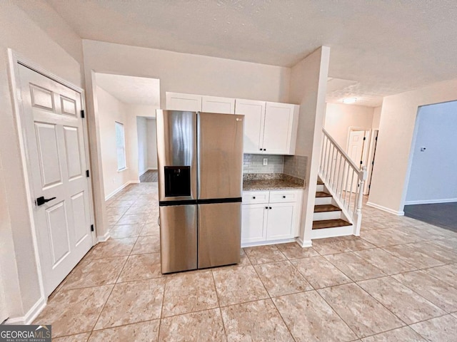 kitchen featuring stainless steel fridge, stone counters, tasteful backsplash, a textured ceiling, and white cabinets