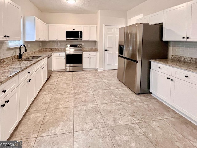 kitchen featuring white cabinetry, sink, stainless steel appliances, and light stone countertops