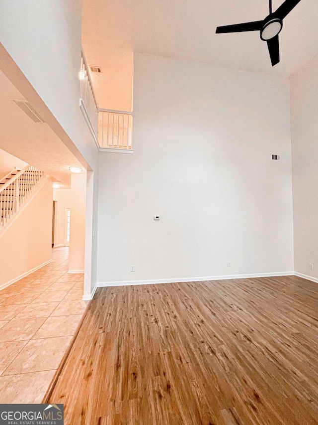 interior space featuring wood-type flooring, a towering ceiling, and ceiling fan