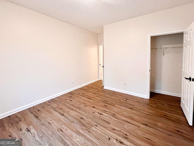 unfurnished bedroom with hardwood / wood-style floors, a closet, and a textured ceiling