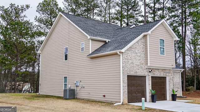 view of side of home with central AC unit and a garage