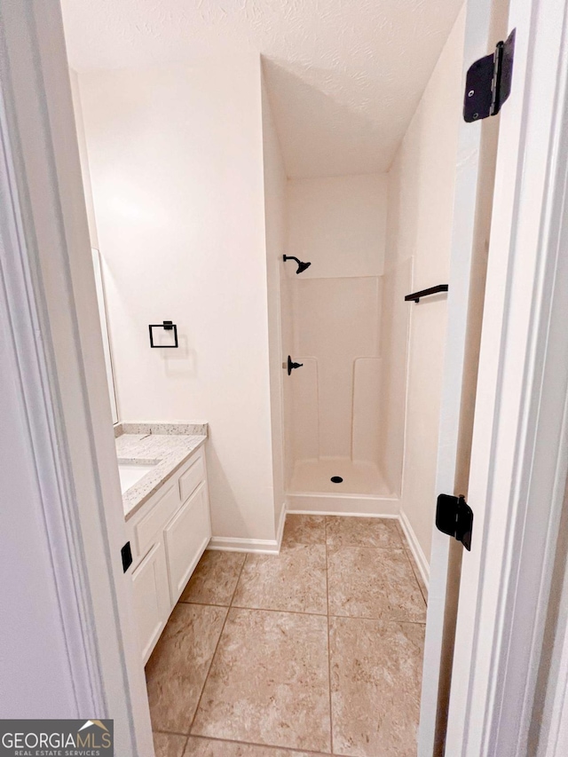 bathroom featuring walk in shower, vanity, and a textured ceiling