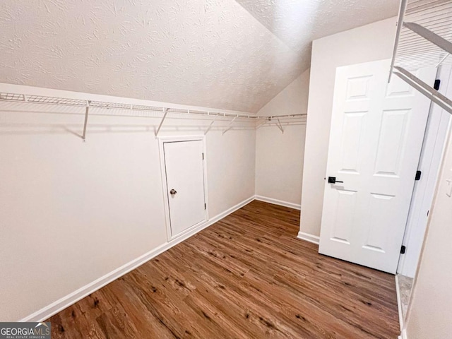 spacious closet featuring hardwood / wood-style floors and vaulted ceiling