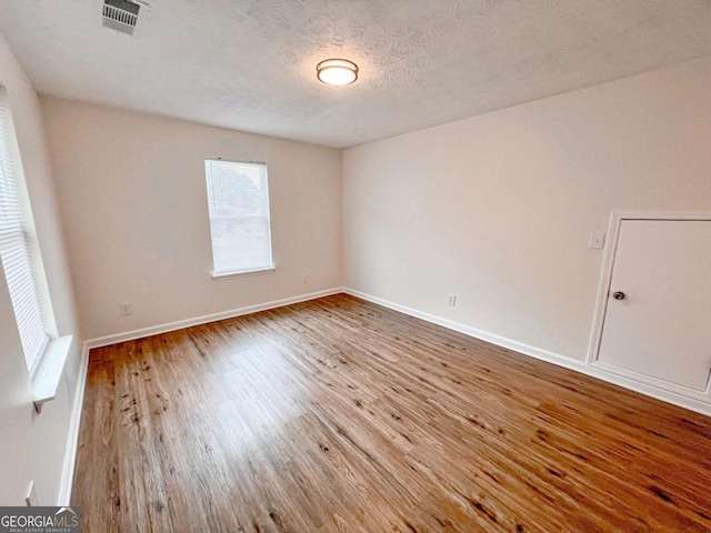 empty room with wood-type flooring and a textured ceiling