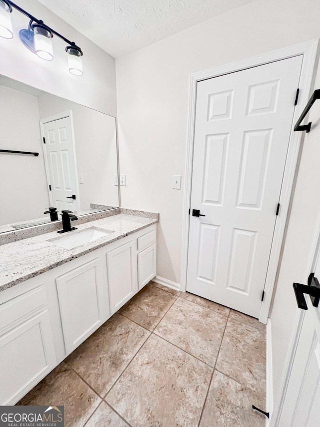 bathroom with tile patterned flooring, vanity, and a textured ceiling