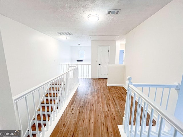 hallway featuring light hardwood / wood-style flooring and a textured ceiling