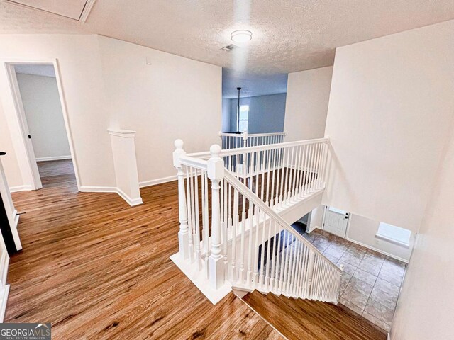 stairs with hardwood / wood-style flooring and a textured ceiling